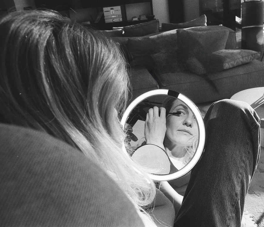 Zane, founder of Vainstal, applying makeup in a round vanity mirror